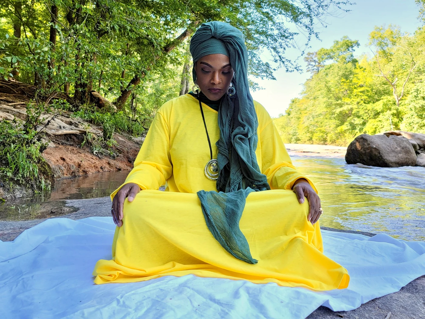 Naaila Moumaris, founder of Auntie NY Counseling, seated in quiet reflection by water
